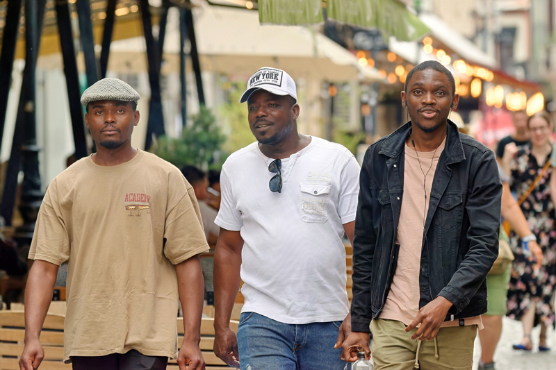 22 - Three black men walking together outdoors in a casual setting, dressed in street-style clothing